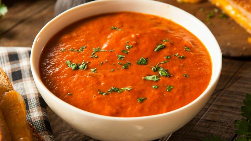 Bowl of tomato soup topped with herbs