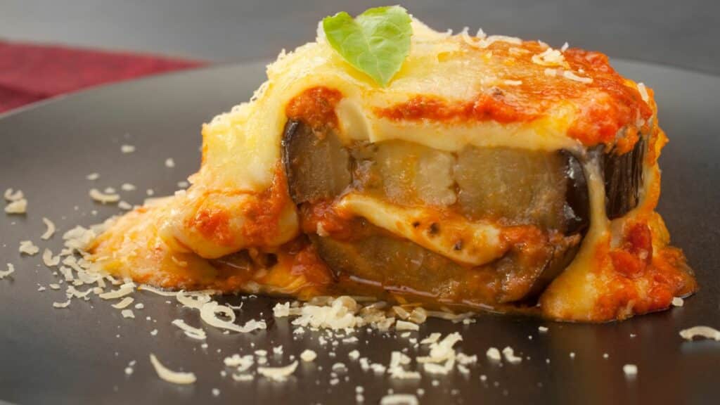 Delicious eggplant lasagna on black plate.