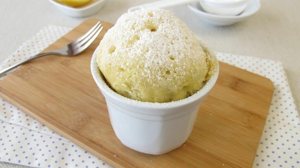 Fluffy mug cake with powdered sugar topping.