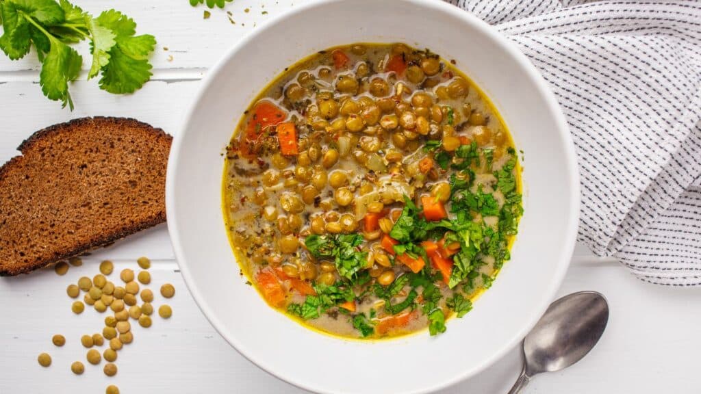 Lentil soup with cilantro and bread slice.