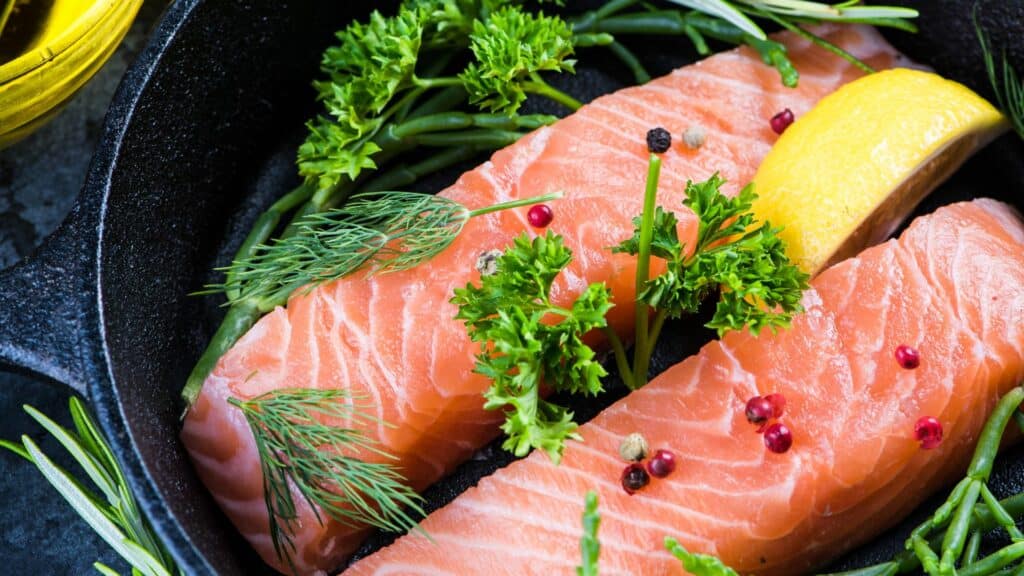 Raw salmon fillets with herbs and lemon slice.