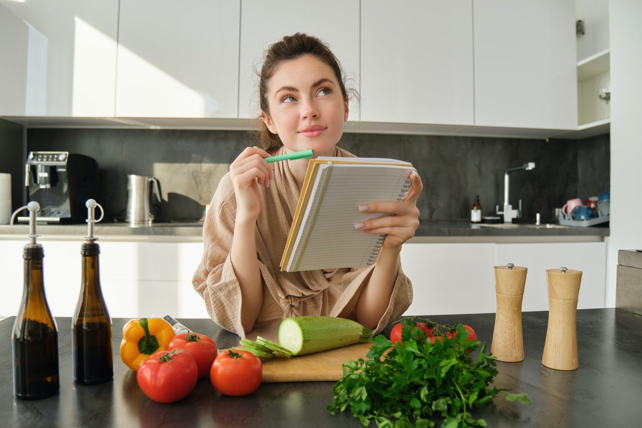 Woman planning recipe with fresh vegetables.
