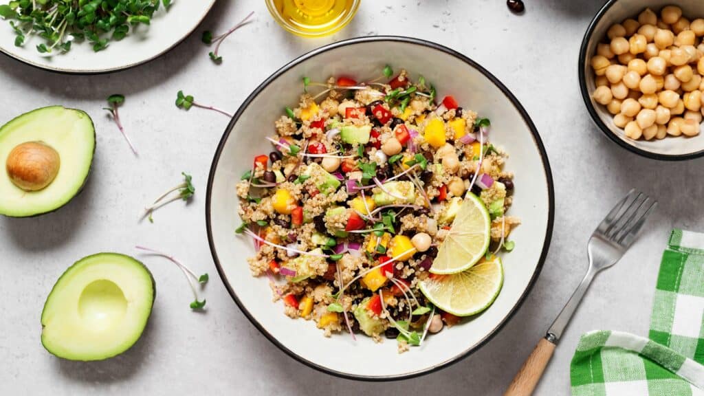 Bowl of quinoa salad with vegetables and lime.