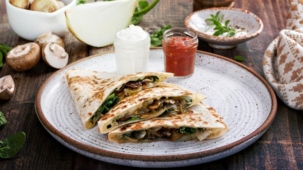 Mushroom spinach quesadillas with sauces on a plate.