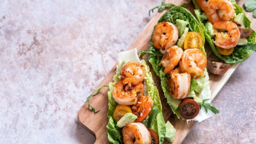 Shrimp lettuce wraps with cherry tomatoes on a board