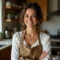 Smiling woman in kitchen wearing apron.