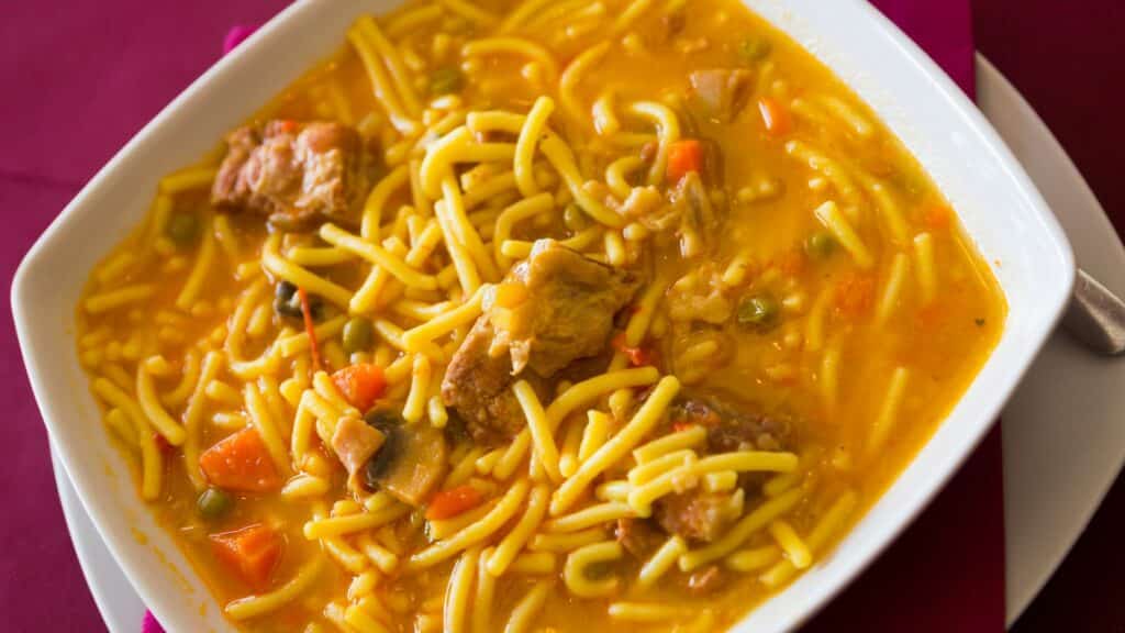 Bowl of noodle soup with vegetables and meat.